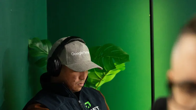 A Setsail strategist in a Google Partner cap and headphones working by the office's green wall.