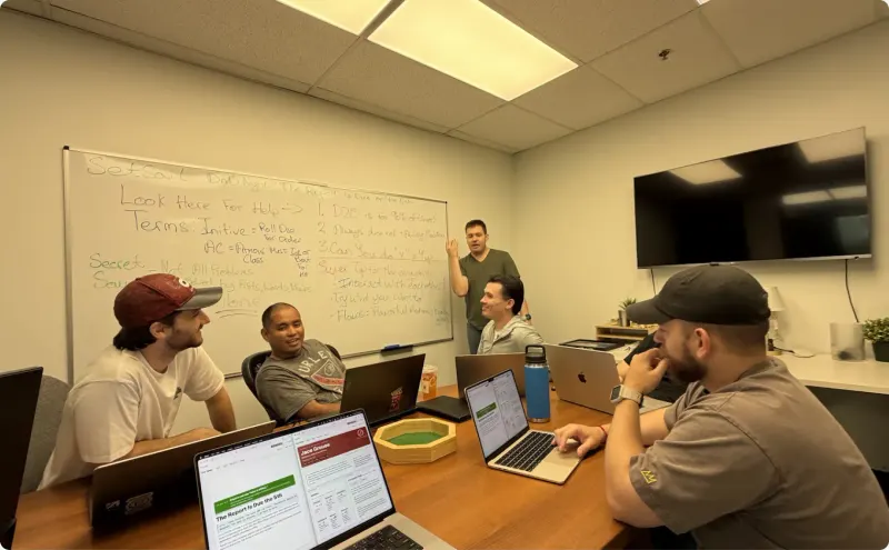 The Setsail team around a meeting-room table with their laptops, one colleague standing at the whiteboard