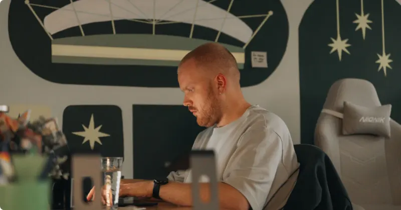A Setsail team member working at his laptop in front of a dark mural